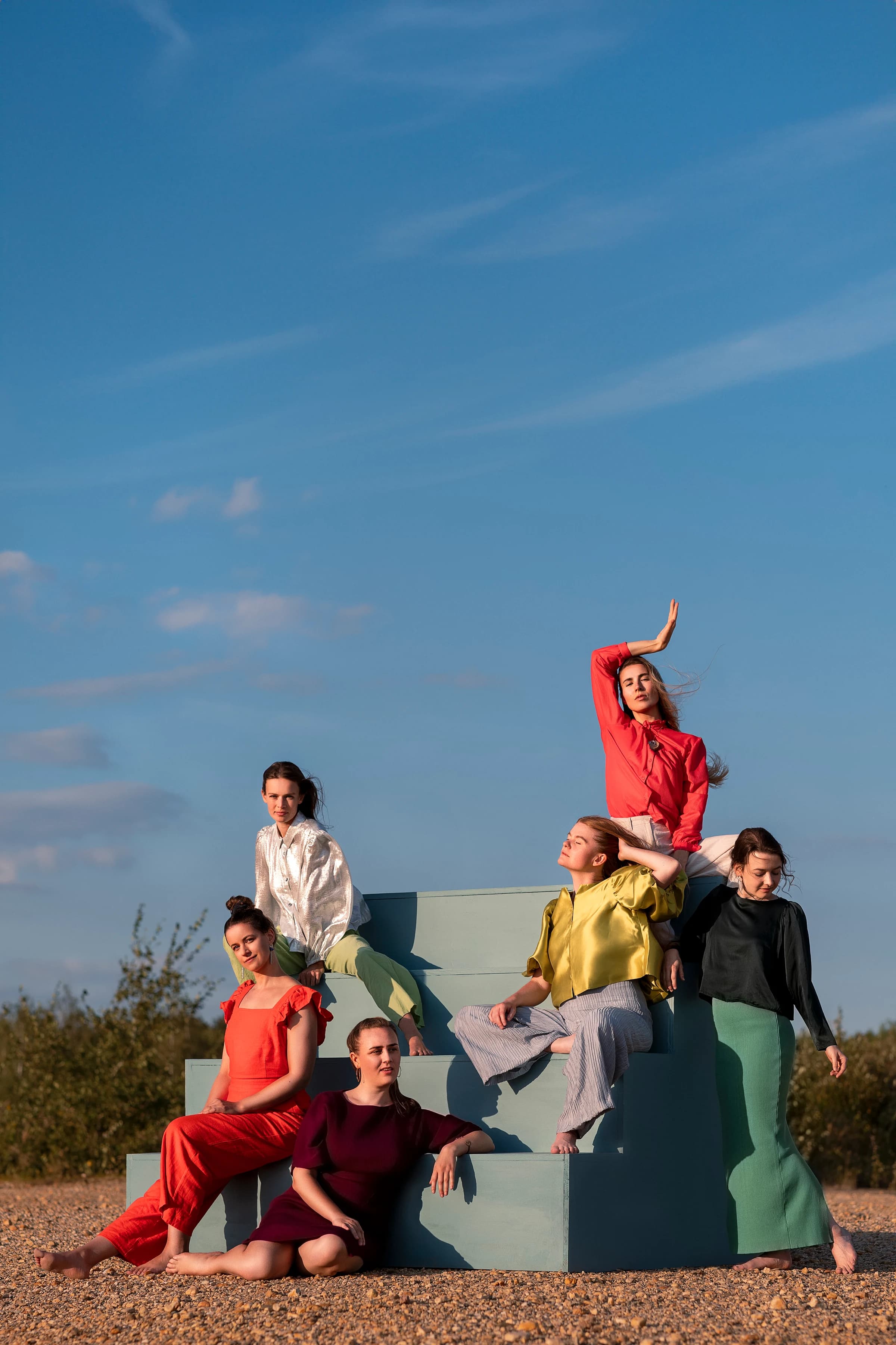 The six singers of Sjaella on green steps under a blue sky